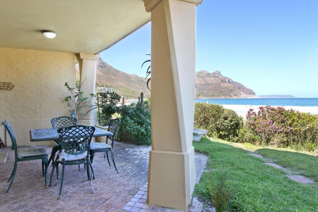 a patio with a table and chairs and the ocean at 9 The Village in Hout Bay