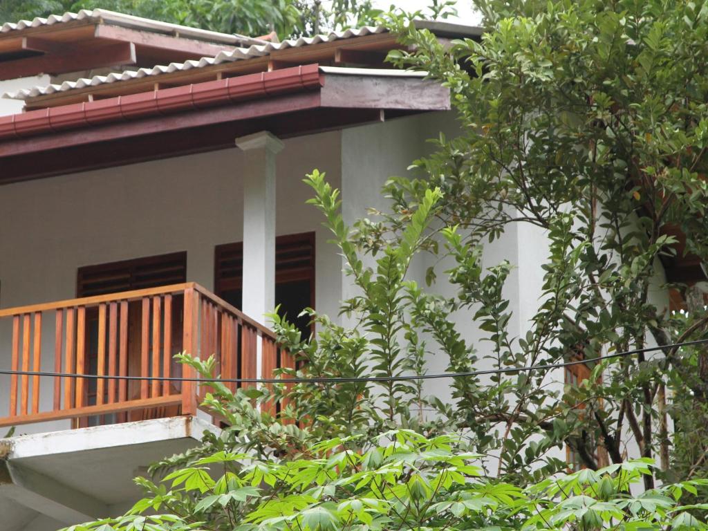 a house with a wooden balcony and trees at lake paradise in Habaraduwa