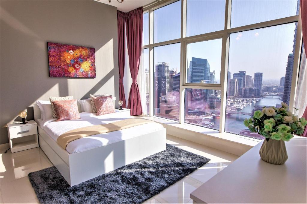 um quarto com uma cama branca e uma grande janela em Luton Vacation Homes - Continental, Dubai Marina no Dubai