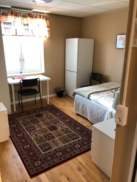 a bedroom with a bed and a desk and a refrigerator at Golden Hostel in Järfälla