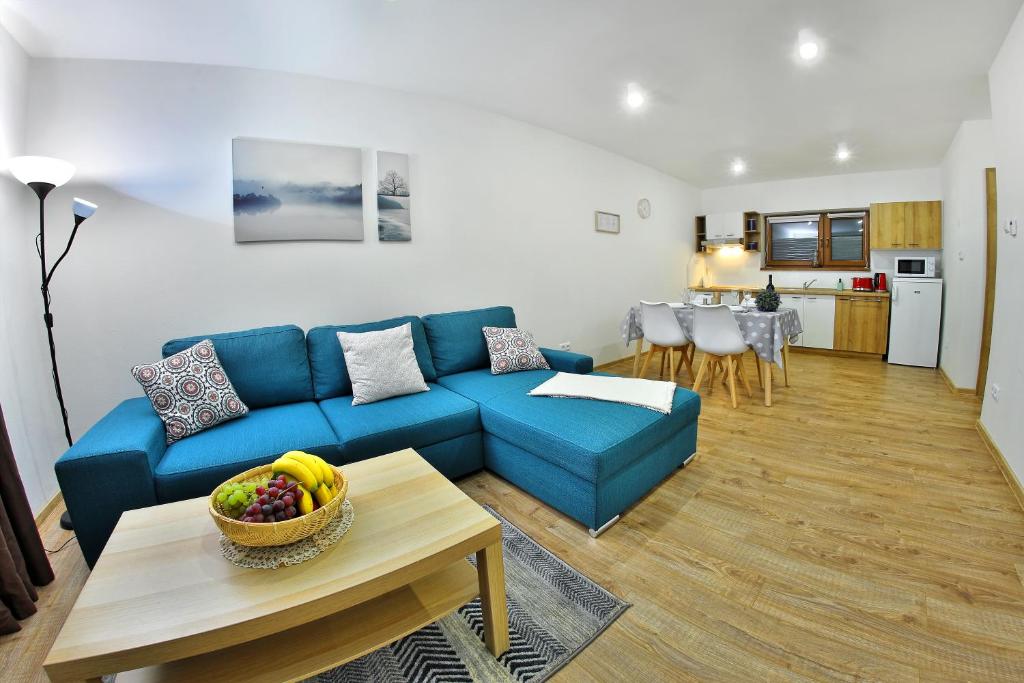 a living room with a blue couch and a table at Kamilli in Bešeňová