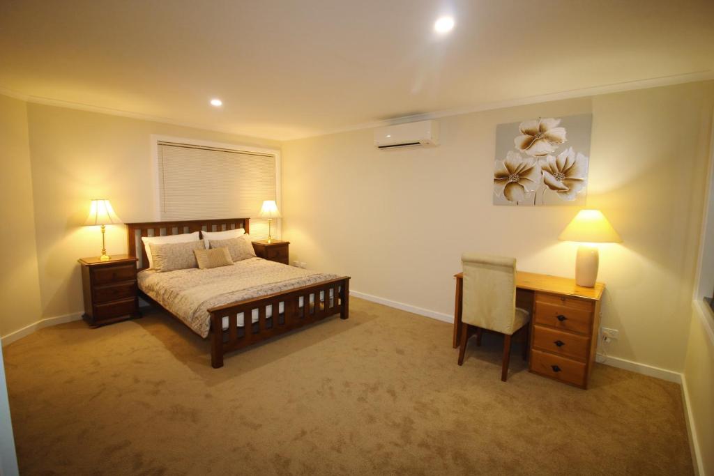 a bedroom with a bed and a desk and two lamps at Silver House - Melbourne Airport Accommodation in Melbourne