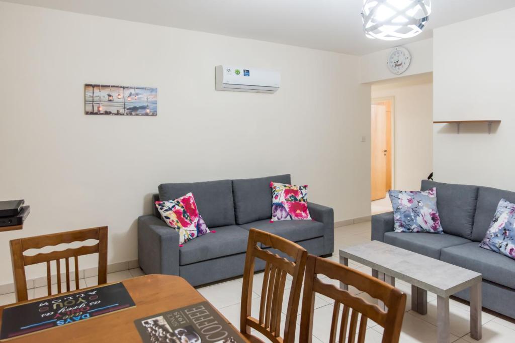een woonkamer met een bank en een tafel en stoelen bij EURO CARISSA FLAT 101 in Larnaka