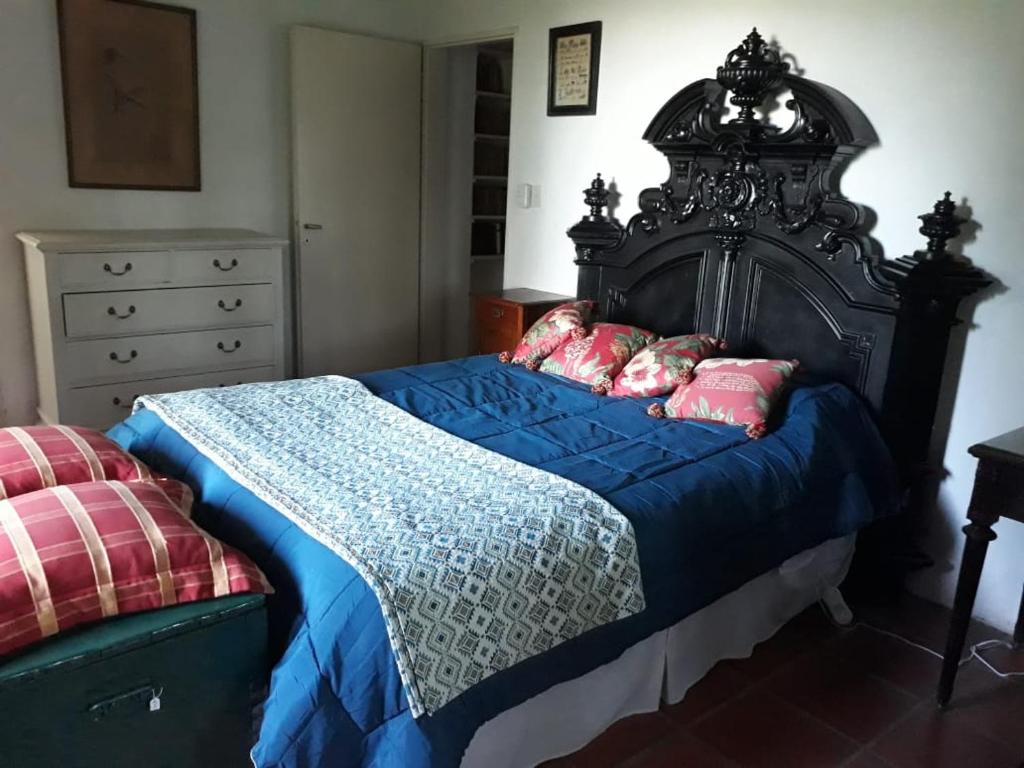 a bedroom with a large bed with blue sheets and pink pillows at El Tramway Casa Antigua de Campo in San Antonio de Areco