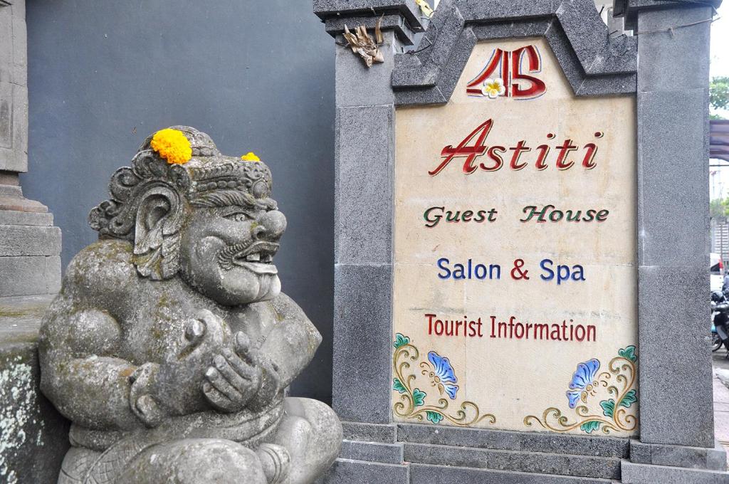 una estatua delante de un cartel de la casa de huéspedes en Astiti Guest House Salon and Spa, en Ubud