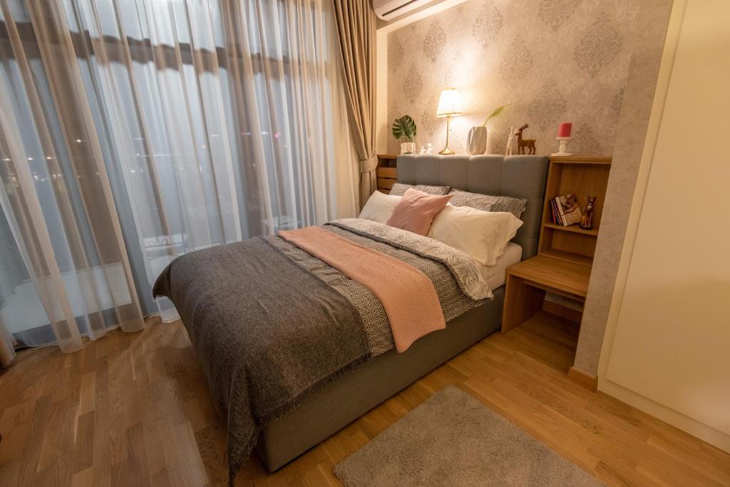 um quarto com uma cama com almofadas e uma janela em Belgrade Waterfront GREEN Apartment em Belgrado