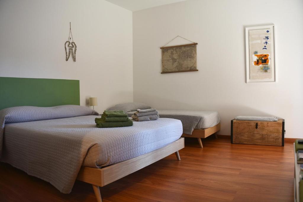 Duas camas num quarto com paredes brancas e pisos de madeira em B&B DEL VIAGGIATORE em Rovereto