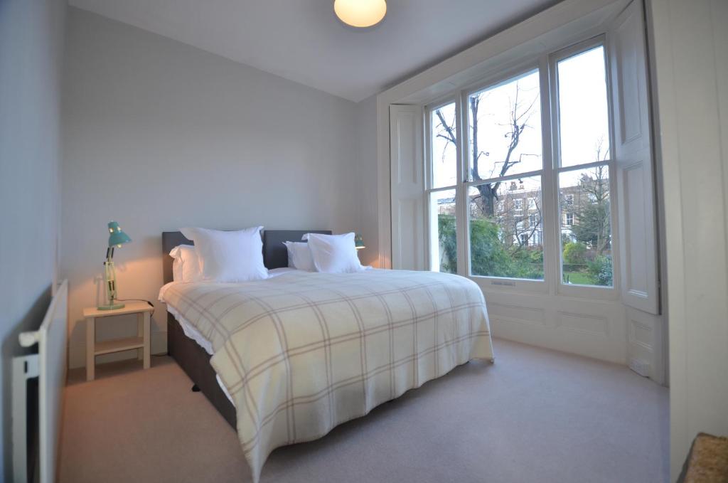 ein weißes Schlafzimmer mit einem Bett und einem Fenster in der Unterkunft Notting Hill Sleeps 5 in London