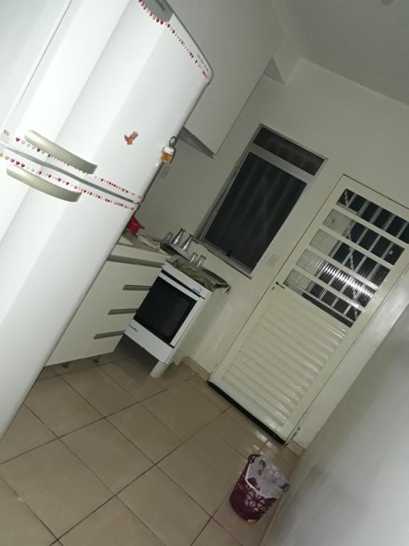 uma cozinha com um frigorífico branco e piso em azulejo em Apartamento Confortável e Seguro em Valparaíso de Goiás