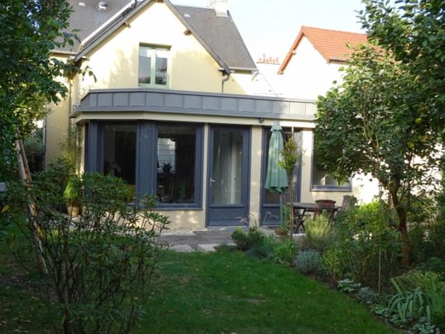 Cette maison dispose d'une terrasse couverte avec une table dans la cour. dans l'établissement Chambre d'hôtes sur jardin acces PMR, à Caen
