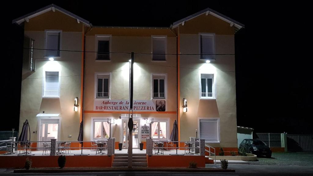 a building with orange chairs in front of it at night at AUBERGE DE LA LICORNE eu in Livron-sur-Drôme