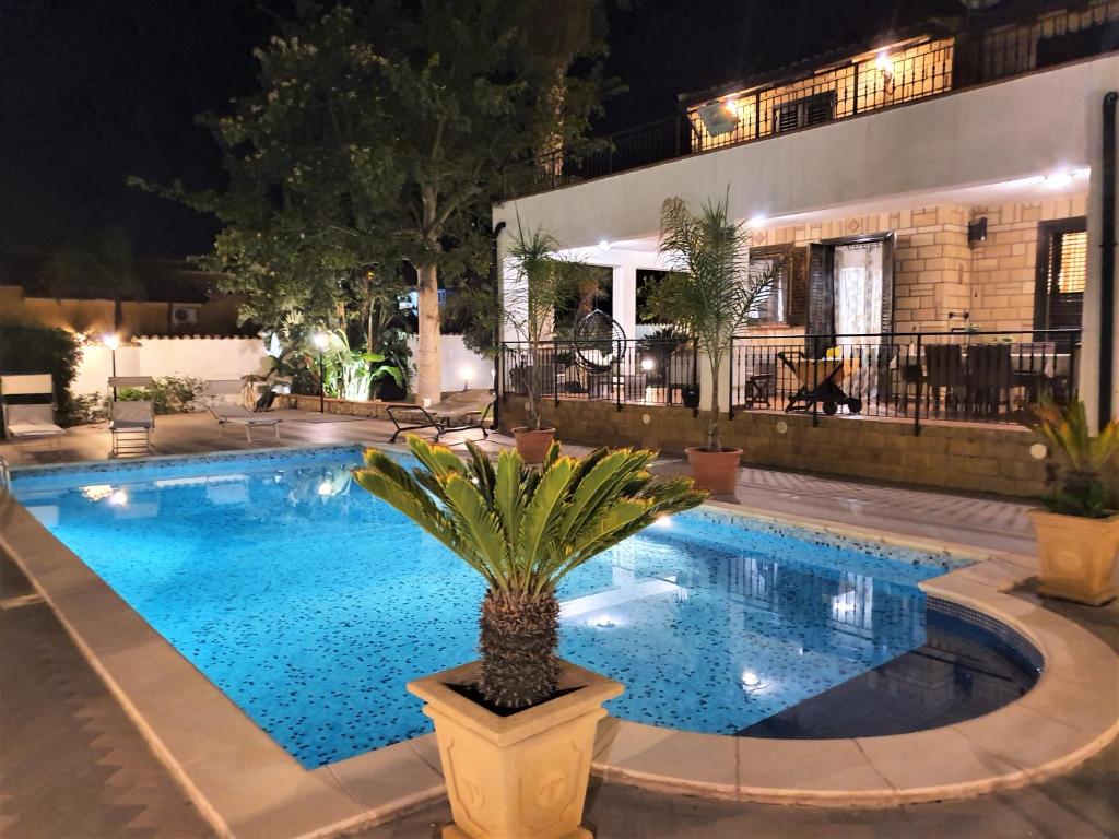 a swimming pool at night with a palm tree in a pot at VILLA MARIANNA CON PISCINA PRIVATA ampi spazi esterni e WIFI FREE in Trabia