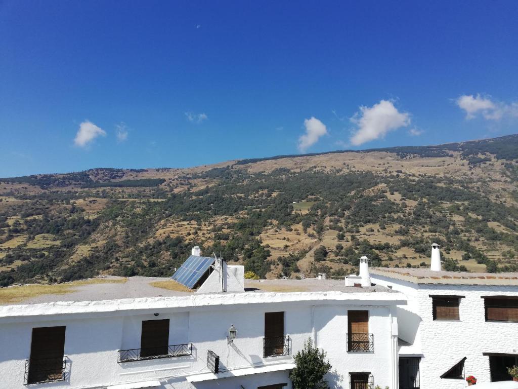a white building with a mountain in the background at Apartamentos Cerro Negro - Las Viñas in Capileira