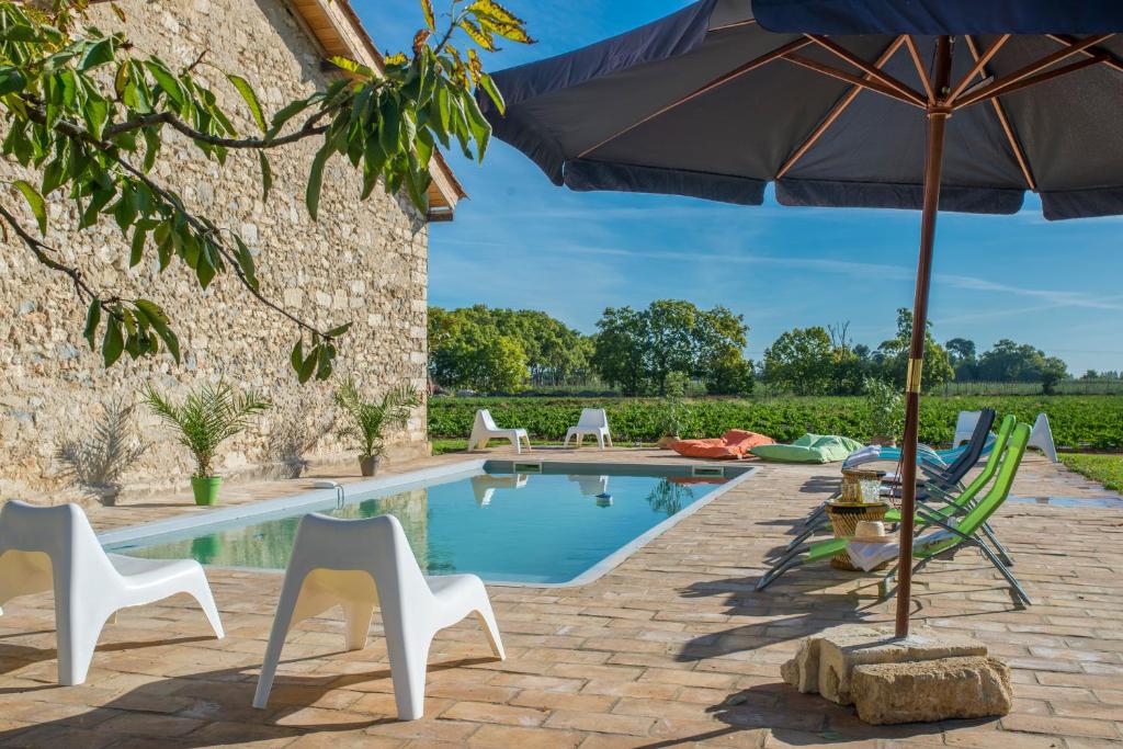 a swimming pool with chairs and an umbrella at Domaine la Clausade in Mauguio