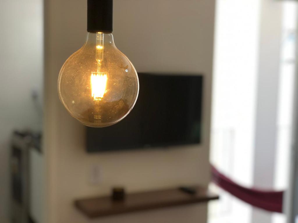eine Glühbirne, die von einer Decke mit einem TV hängt in der Unterkunft Maravilhoso apartamento em Salvador (Barra) in Salvador