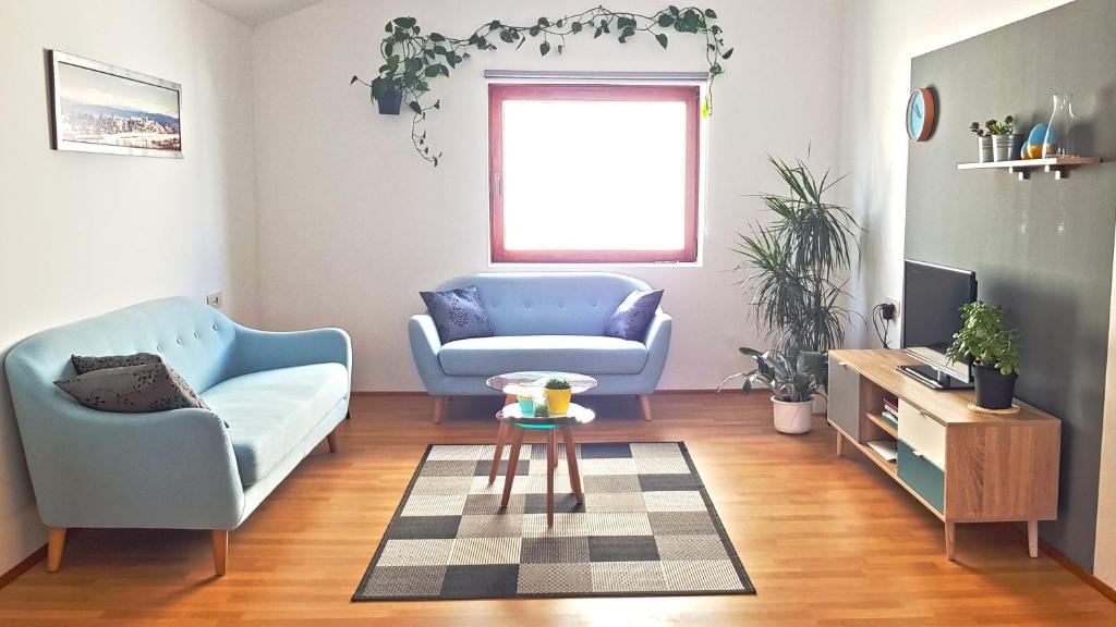 uma sala de estar com duas cadeiras azuis e uma mesa em Apartman 13 em Križevci