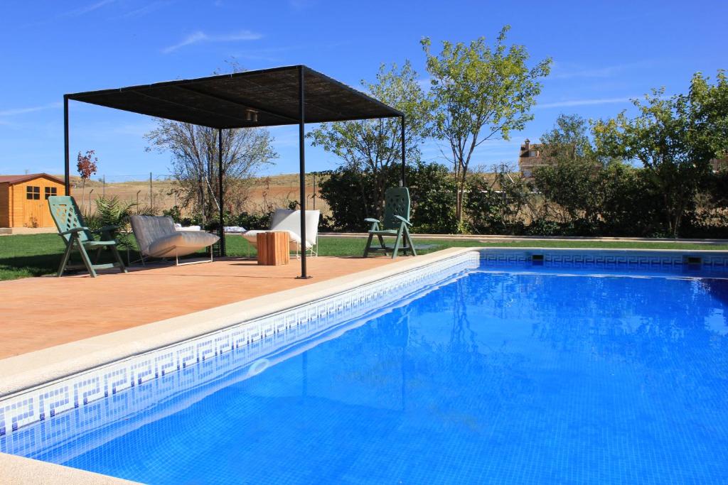 a swimming pool with an umbrella and a table and chairs at Finca Paredes in Valdetorres de Jarama