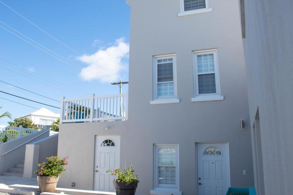 a white house with two doors and two potted plants at Cavendish Heights Suites in Pembroke