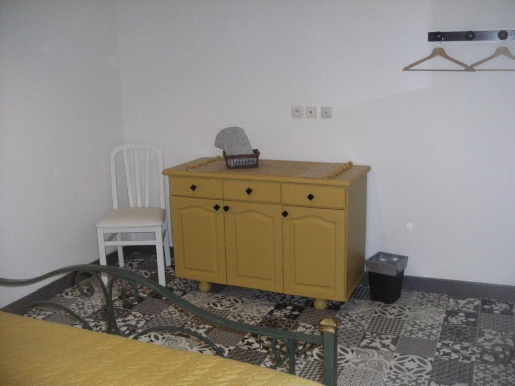 a yellow cabinet in a room with a chair at grange dans ancien corps de ferme in Bellengreville