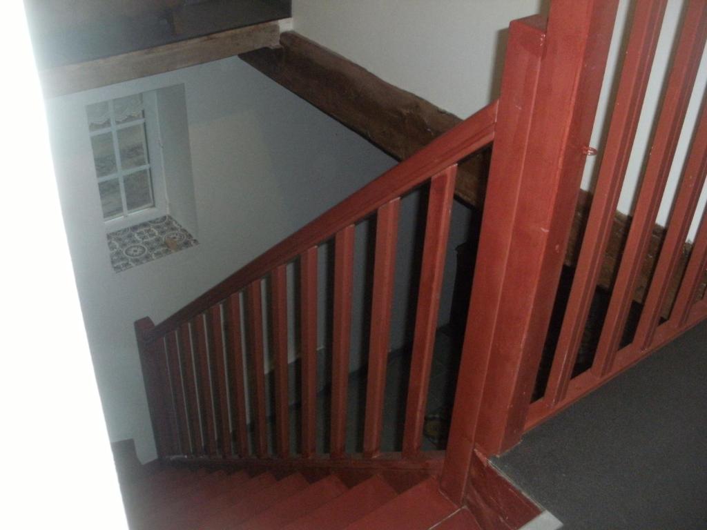 a wooden staircase with a wooden rail and a window at grange dans ancien corps de ferme in Bellengreville