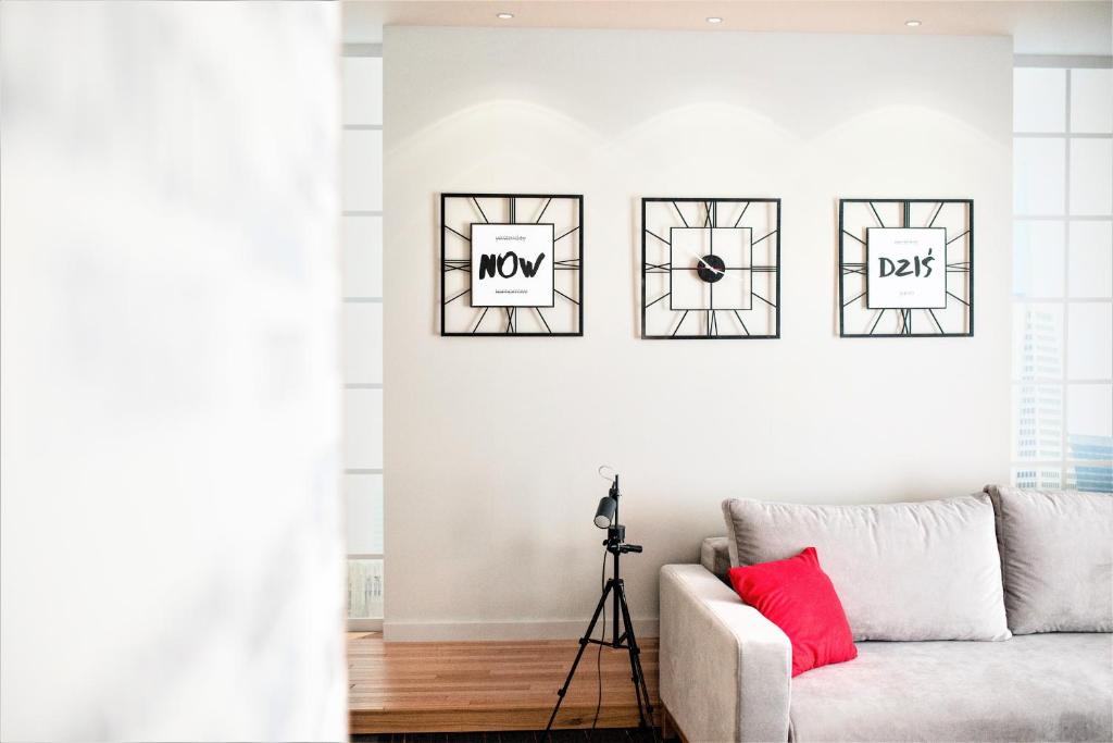 a living room with a couch and four pictures on the wall at Apartamenty Czestochowa Eu "parking gratis" in Częstochowa