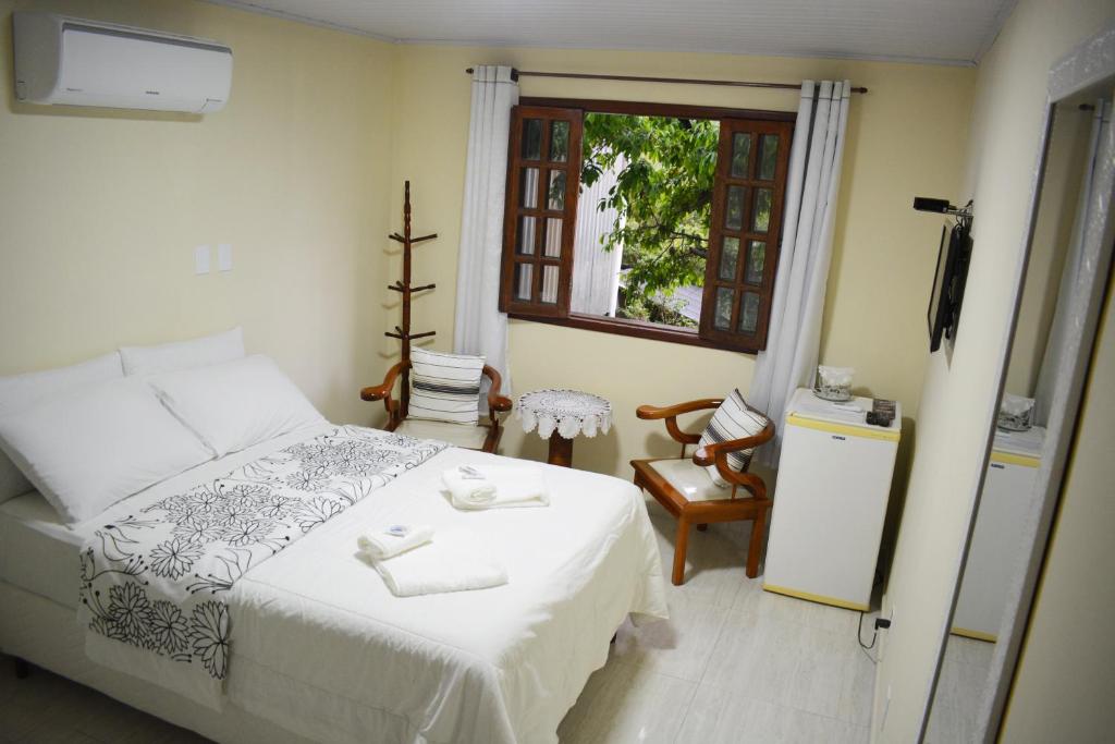 1 dormitorio con cama blanca y ventana en Nova Suíte - centro de Domingos Martins + Café da manhã en Domingos Martins
