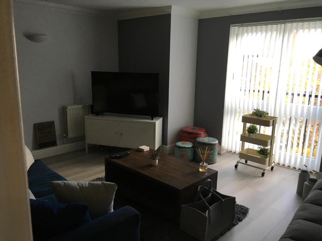 a living room with a tv and a couch and a table at Godwin Court 21 in Swindon