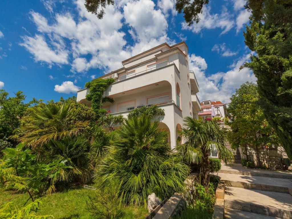 a white building with palm trees in front of it at Apartments Vanessa in Dramalj