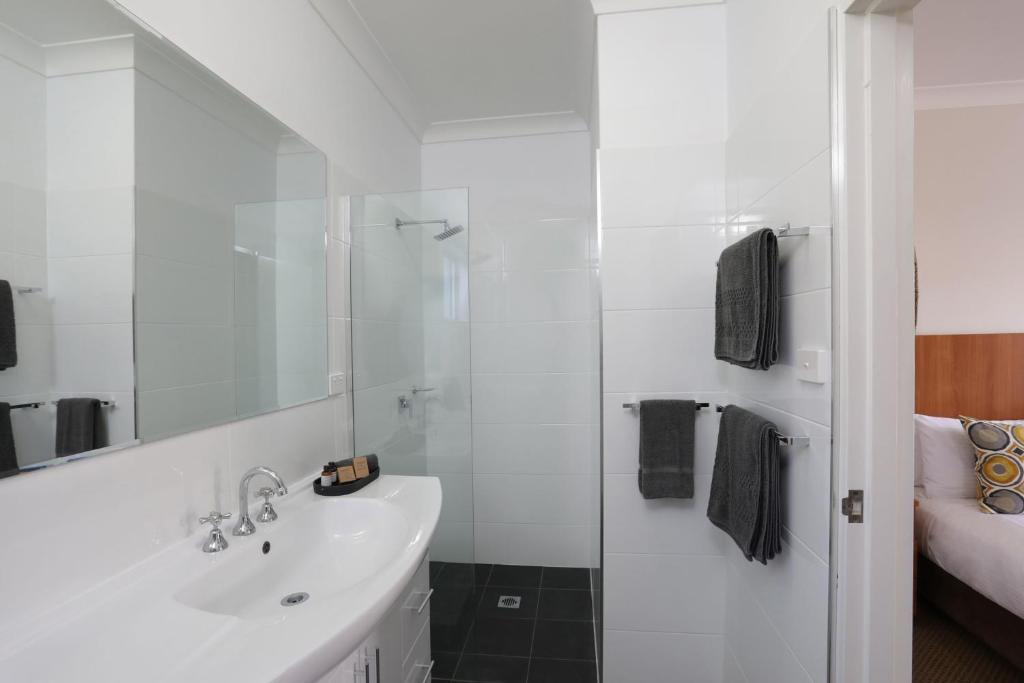 a white bathroom with a sink and a shower at Cadman Motor Inn and Apartments in Tamworth