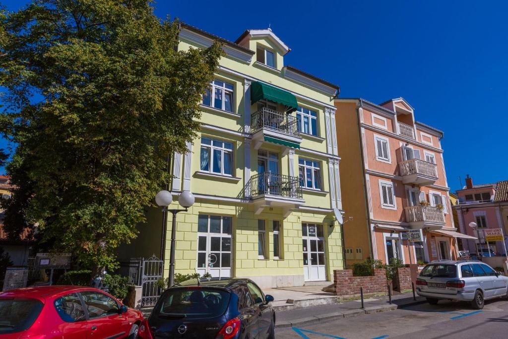 a yellow building with cars parked in front of it at Apartments Villa Katarina in Selce