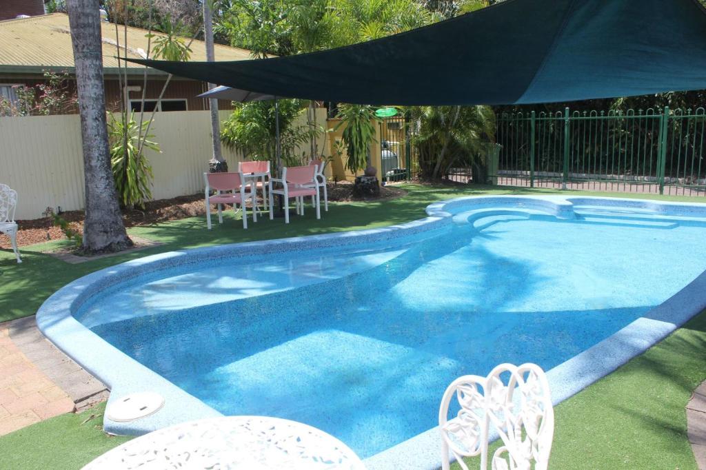 a swimming pool with chairs and an umbrella at Paravista Motel in Darwin