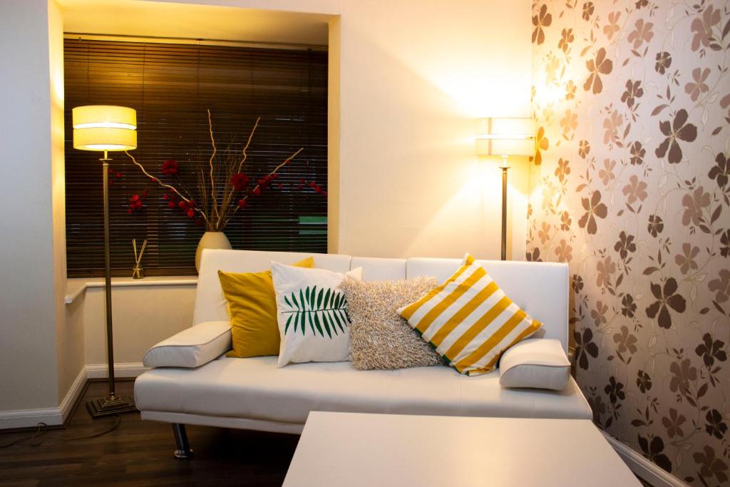 a living room with a white couch with colorful pillows at Kempston Cosy Lodge in Bedford