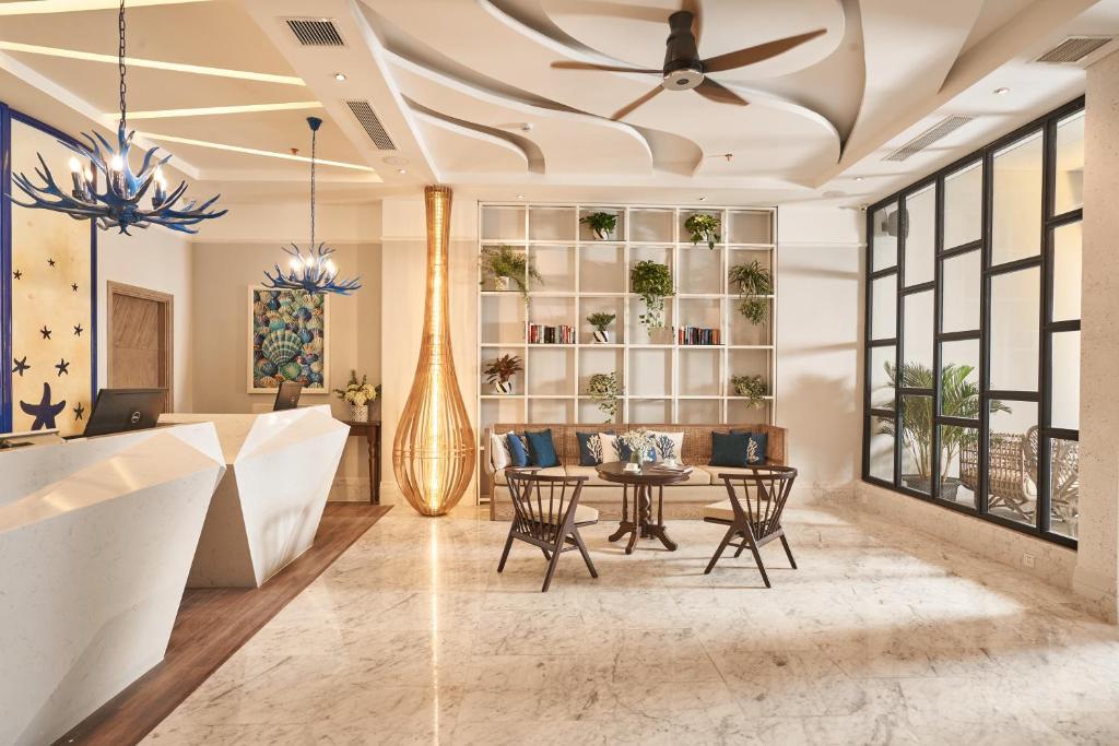 a living room with a ceiling fan and a table at Sofiana My Khe Hotel & Spa- Rooftop Pool Bar in Danang
