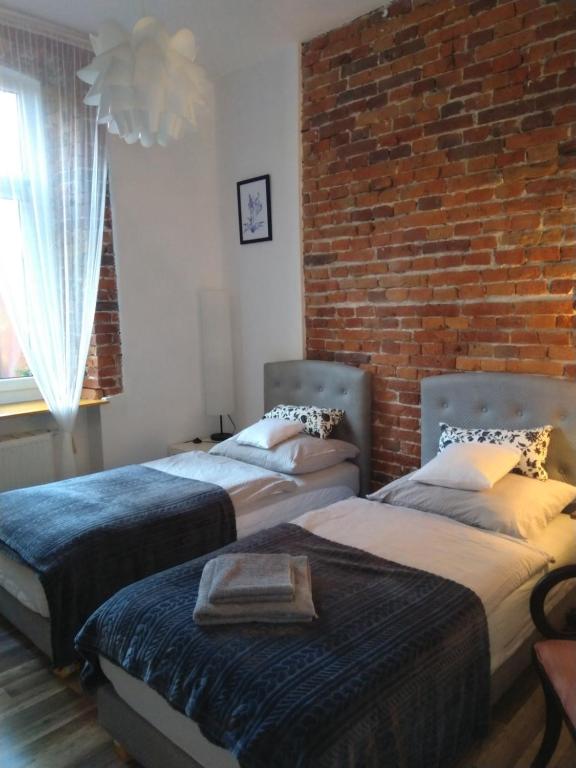 2 camas en una habitación con una pared de ladrillo en Tenczynska 4 B Starówka Aparts by Homeprime, en Cracovia