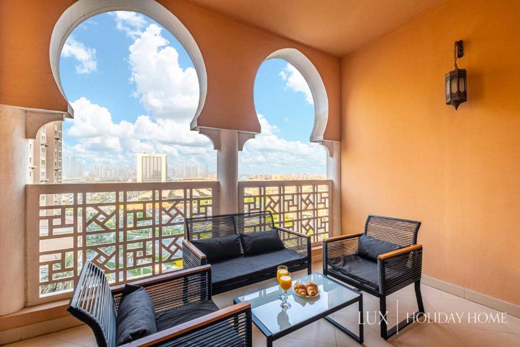 a balcony with two chairs and a table and a window at LUX - IBN Battuta Residence in Dubai