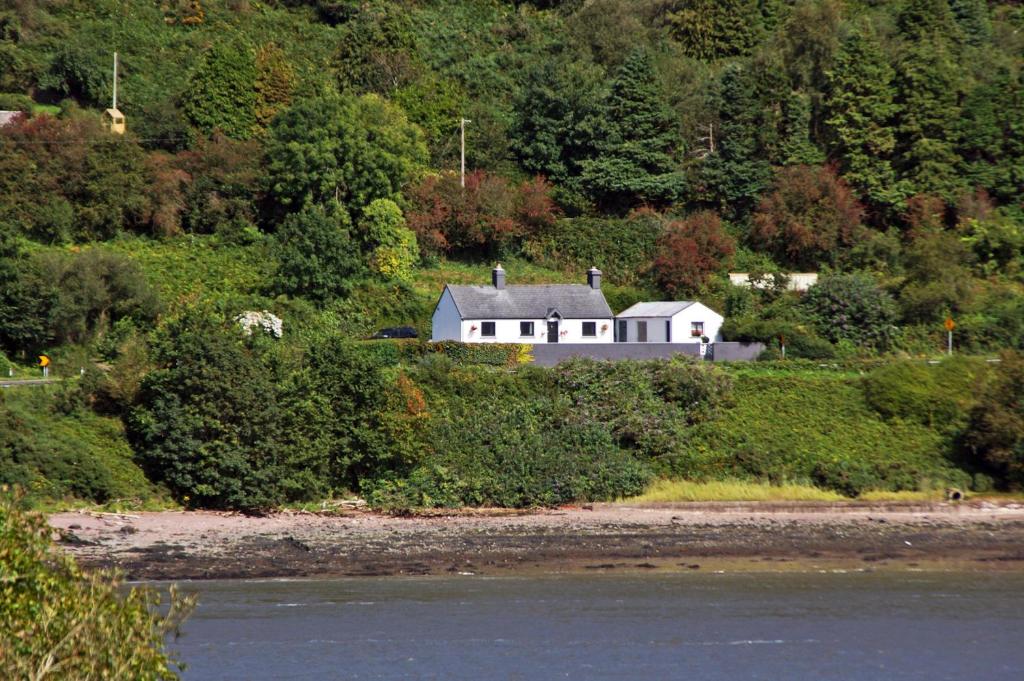 a house on a hill next to a body of water at Cottage at Youghal Bridge in DʼLoughtane Cross Roads