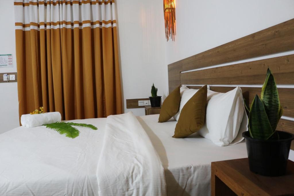 1 dormitorio con 1 cama con sábanas y almohadas blancas en Rasdhoo Wave Blue, en Rasdu