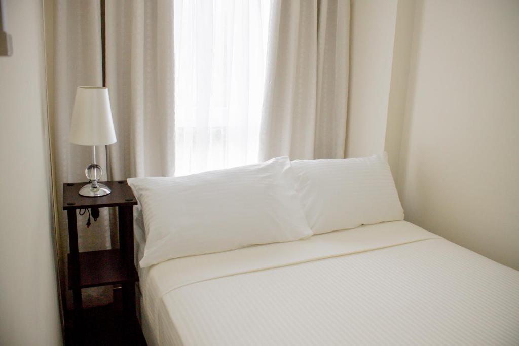 a white bed with white pillows and a window at Sitio Uno Residences in Roxas City