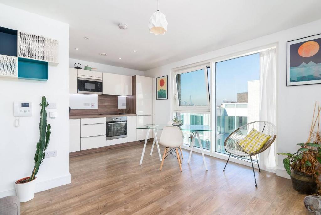 a kitchen with white cabinets and a table and chairs at Lovely studio flat with terrace in Southeast London in London