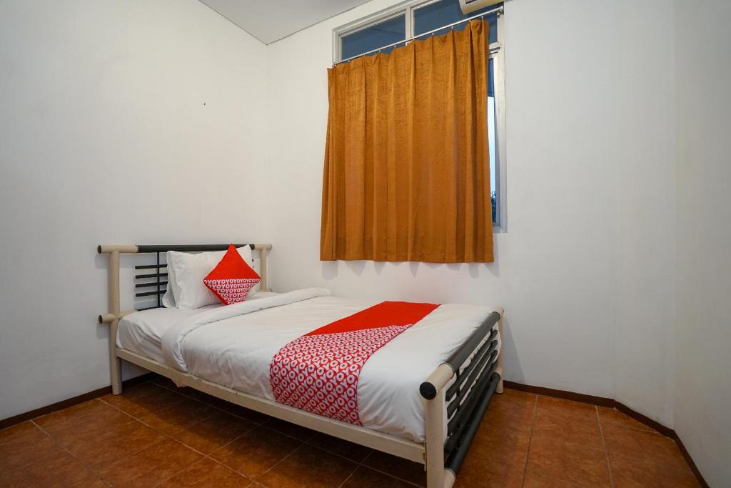 a small bedroom with a bed and a window at Super OYO 1844 Bravo Residence in Pangkalpinang