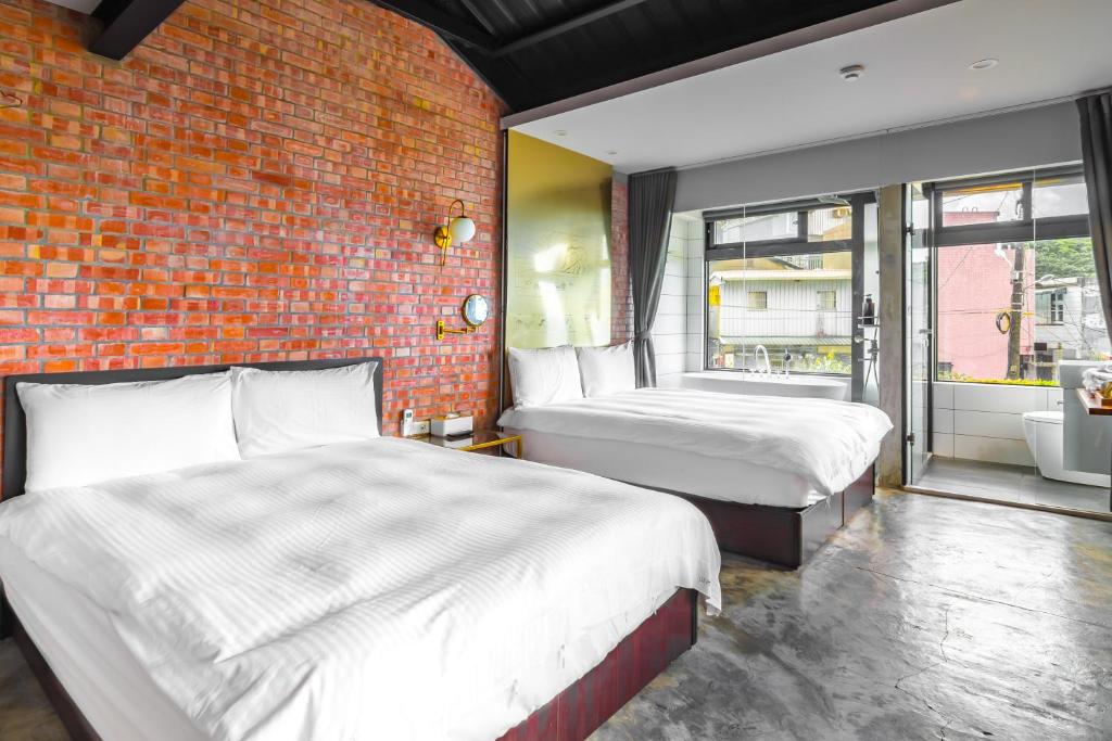 two beds in a room with a brick wall at H&amp; Jiufen Ore Inn in Jiufen