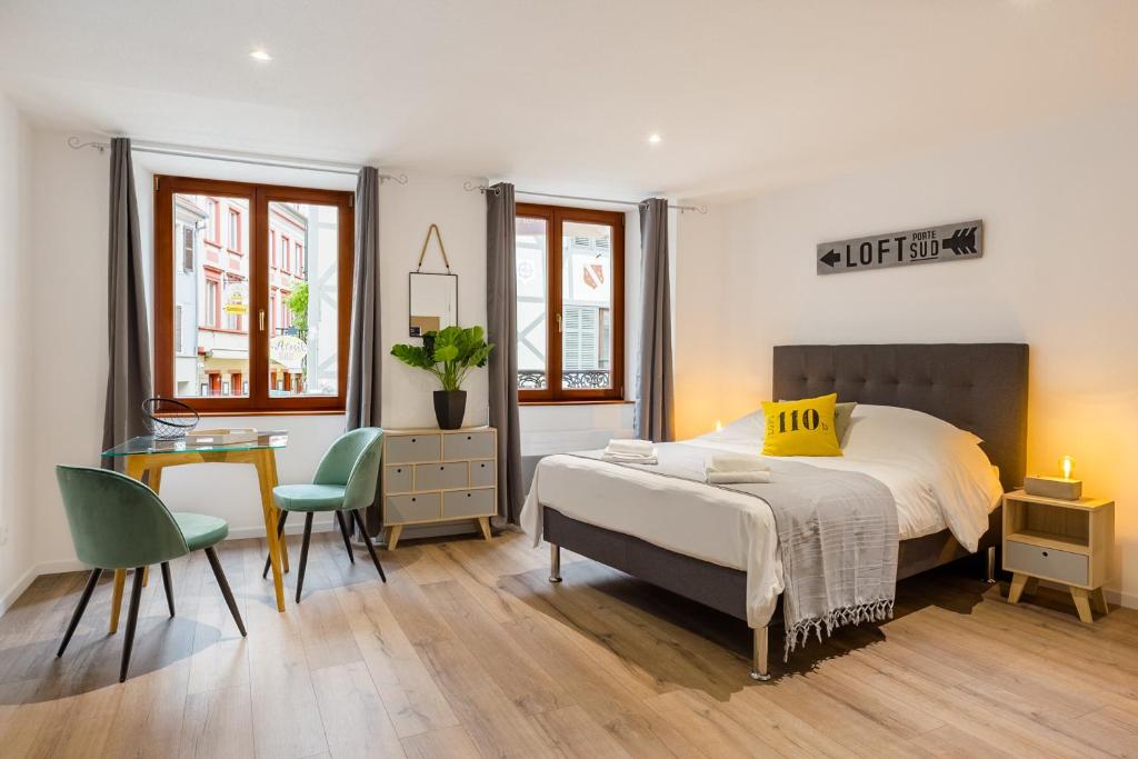 Schlafzimmer mit einem Bett, einem Tisch und Stühlen in der Unterkunft Travel Homes - L'Arsenal, studios en hyper centre in Mulhouse