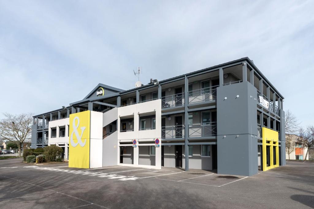 un immeuble de bureaux avec un jaune et un blanc dans l'établissement B&B HOTEL Nantes Parc Expos La Chapelle, à La Chapelle-sur-Erdre