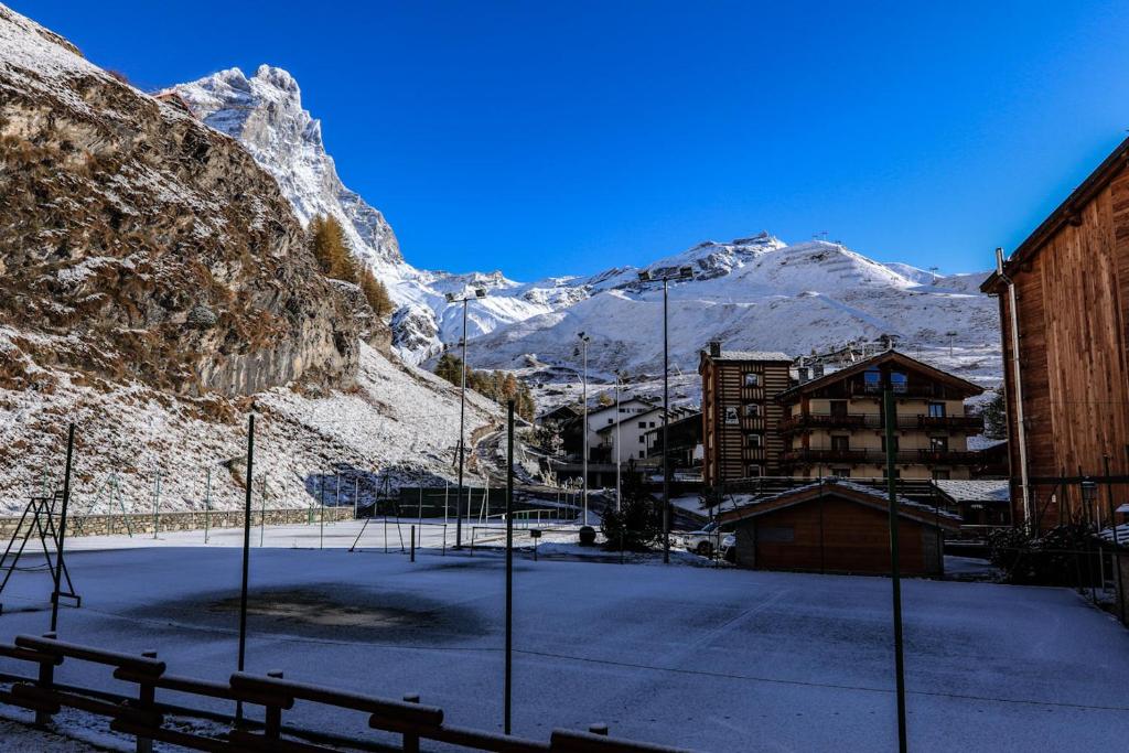 een parkeerplaats met een gebouw en een met sneeuw bedekte berg bij oasi budden 2 in Breuil-Cervinia