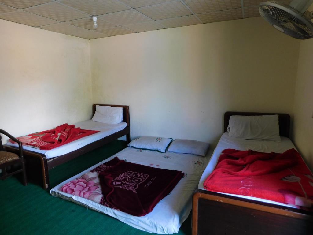 2 camas en una habitación pequeña con sábanas rojas en Hamaliya Hotel & Restaurant en Bālākot