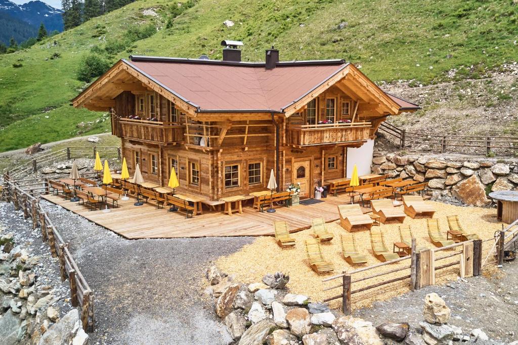 a large wooden cabin with tables and chairs in front at Apartchalet Jörglerhof in Gerlos