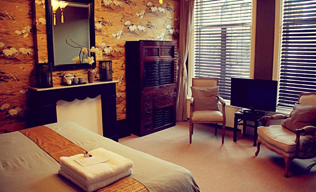 een slaapkamer met een bed, een bureau en een televisie bij Maison Indochine in Den Haag