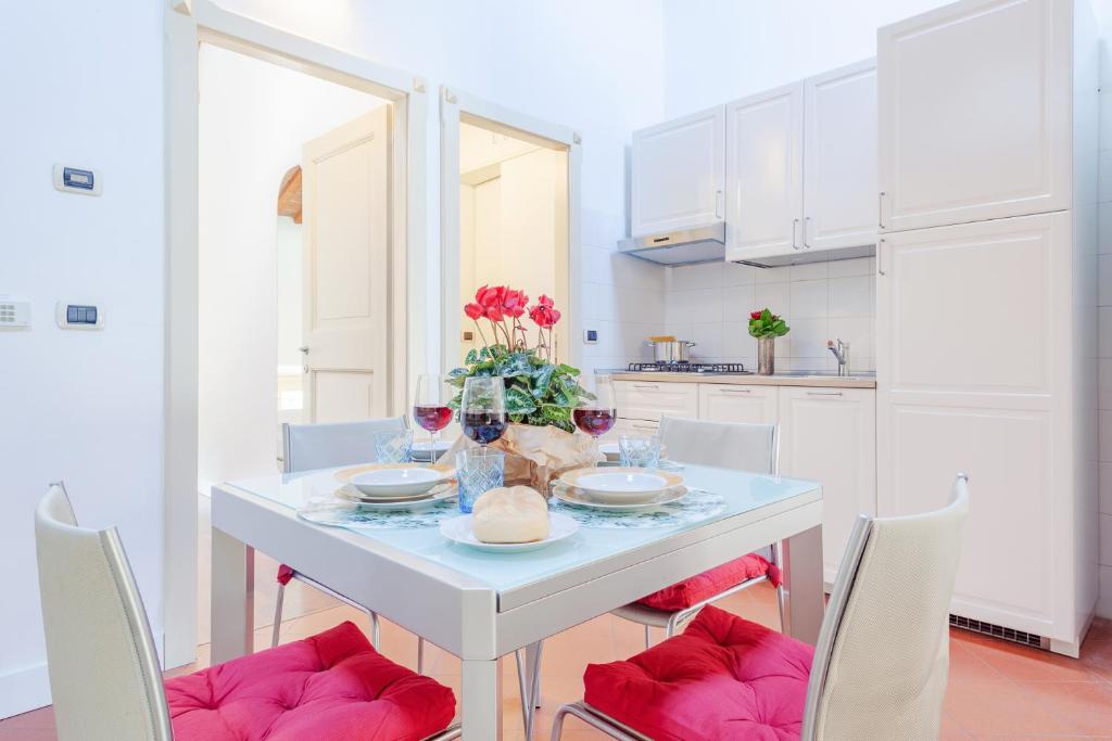 a white kitchen with a white table and chairs at Ex Tribunale Palazzo Bentivoglio Apartment in Ferrara
