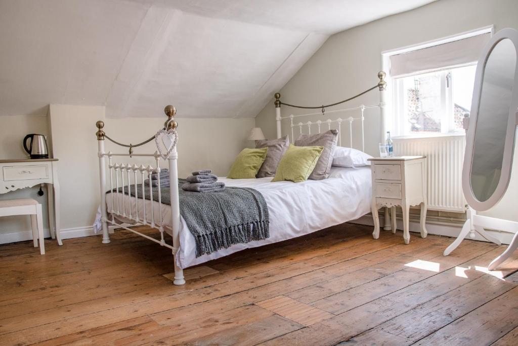 a bedroom with a white bed and a wooden floor at The Golden Key in Snape