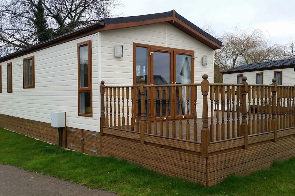 ein kleines Haus mit einem Holzzaun und einer Veranda in der Unterkunft Carnoustie Lodge in Wisbech